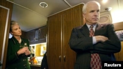 Republican presidential candidate Arizona Senator John McCain listens to advice from his campaign staff onboard his bus as his wife, Cindy, looks on near Concord, New Hampshire, Jan. 25, 2000.