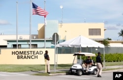 Security guards stand outside a former Job Corps site that now houses child immigrants, June 18, 2018, in Homestead, Fla. It is not known if the children crossed the border as unaccompanied minors or were separated from family members.