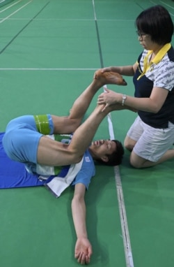 Chou Tien-chen dari Taiwan, pebulu tangkis nomor dua dunia sedang dibantu peregangan oleh fisioterapinya, Victoria Kao (kanan), di Taipei, 30 Agustus 2019. (Foto: AFP)
