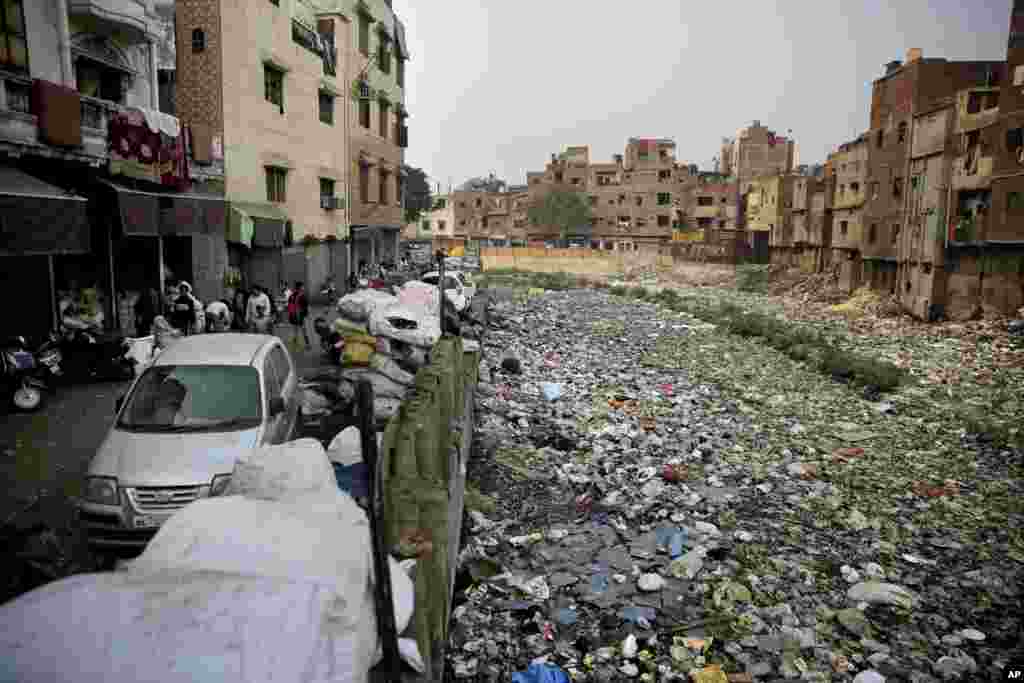 FILE - Piles of electronic waste is placed next to a drain chocked with plastic and garbage in New Delhi, India,Dec. 8, 2018.