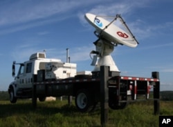 A NOAA mobile storm-chasing radar vehicles is deployed outside a bat cave at dusk.
