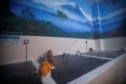 Orang-orang berendam di bak mandi dengan lukisan Gunung Fuji di dinding pemandian umum Jepang, atau sento, 'Dai-ni Takara-yu' di Tokyo, Jepang 25 November 2021. (Foto: REUTERS/Issei Kato)
