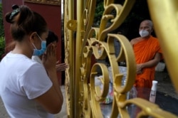 ប្រជាពលរដ្ឋកម្ពុជាប្រគេនចង្ហាន់និងបច្ច័យដល់ព្រះសង្ឃ ក្នុងអំឡុងពេលបុណ្យភ្ជុំ នៅរាជធានីភ្នំពេញ កាលពីថ្ងៃទី ២៤ ខែកញ្ញា ឆ្នាំ ២០២១ ក្នុងអំឡុងវិបត្តិរាតត្បាតនៃជំងឺកូវីដ១៩។