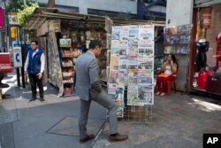 A man stops to read headlines, many featuring U.S. President Donald Trump's actions to jump-start construction on a promised border wall and his insistence that Mexico will foot the bill, in Mexico City, Jan. 26, 2017.