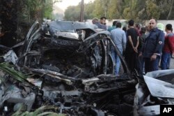 This photo released by the Syrian official news agency SANA shows Syrians gathered next to a car hit by shelling by members of the Army of Islam rebel group at Rabwa neighborhood in Damascus, Syria, April 6, 2018.