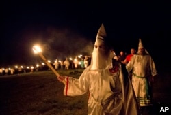 In this Saturday, April 23, 2016 photo, members of the Ku Klux Klan participate in cross burnings after a "white pride" rally in rural Paulding County near Cedar Town, Ga. Born in the ashes of the smoldering South after the Civil War, the KKK died and was reborn before losing the fight against civil rights in the 1960s. Membership dwindled, a unified group fractured, and one-time members went to prison for a string of murderous attacks against blacks. Many assumed the group was dead, a white-robed ghost of hate and violence.