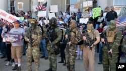 FILE - In this May 2, 2020, fphoto, people, including those with the boogaloo movement, demonstrate against business closures due to concern about COVID-19, at the State House in Concord, N.H.