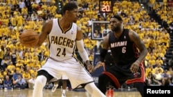 Le joueur-vedette des Indiana Pacers Paul George (24), à gauche, tente un drible face à LeBron James (6) de Miami Heat lors d'un match de basketball de la NBA, le 28 mars 2014.