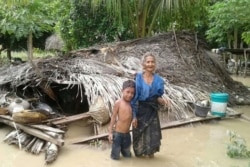 Seorang nenek dan cucunya berdiri depan rumah mereka yang rusak akibat banjir bandang di Desa Haitimuk di Flores Timur pada 4 April 2021. Banjir bandang dan tanah longsor melanda Indonesia bagian timur dan negara tetangga, Timor Leste. (Foto: AFP/Joy Chr