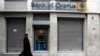 A Greek Orthodox priest walks a branch of Bank of Cyprus in Athens March 19, 2013.