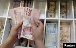 A money changer counts Turkish lira bills at an currency exchange office in central Istanbul, Turkey, Aug. 21, 2015. President Tayyip Erdogan's has asked Turks to convert their dollars and euros to lira.