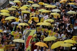 Protesters carry yellow umbrellas during a rally in a downtown street to support for a veto of the government’s electoral reform package in Hong Kong, June 14, 2015.