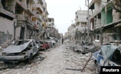 The damaged cars and buildings are seen in the besieged town of Douma, Eastern Ghouta, Damascus, Feb. 25, 2018.