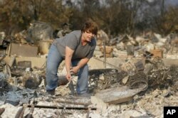 Tammy Christiansen searches the remains of her Coffey Park neighborhood home, Oct. 11, 2017, in Santa Rosa, California. During her search she found her wedding ring and her son's wrestling trophy.