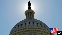 FILE - The U.S. flag flies next to the Capitol in Washington, July 14, 2011. The House of Representatives is to vote shortly on new sanctions against Russia for its meddling in last year's presidential election.