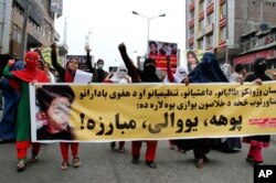 FILE - Women march as they hold photos showing ethnic Hazara victims who were allegedly beheaded by the Taliban, in Jalalabad, east of Kabul, Nov. 12, 2015.