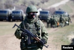 An armed man, believed to be a Russian soldier, stands on guard outside a military base in Perevalnoye, near the Crimean city of Simferopol, March 21, 2014.