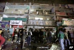 FILE - People gather in front of the mall in Baghdad, Iraq, on Jan. 11, 2016. Gunmen stormed into the mall Monday, spraying bullets at shoppers before blowing themselves up.