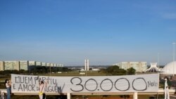 Artists hold a banner reading "Who's gone is someone's love, 30,000 dead" amid the coronavirus disease (COVID-19) outbreak in Brasilia