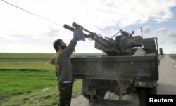 FILE - A Free Syrian Army fighter cleans an anti-aircraft artillery gun near the Menagh military airport in Aleppo's countryside, Feb. 17, 2013.