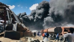 FILE - People are seen in front of clouds of black smoke from fires in the aftermath at the scene of an airstrike in Mekele, the capital of the Tigray region of northern Ethiopia on Oct. 20, 2021