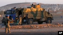 FILE - Turkish soldiers stand guard at a checkpoint as Syrian refugees from Kobani arrive at the Turkey-Syria border crossing of Mursitpinar near Suruc, Turkey, Oct. 1, 2014. Less fortunate refugees have reported being shot at at points along the entire Turkey-Syria border.