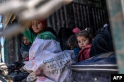 Children sit together in a truck as a convoy of vehicles led by U.S.-backed Syrian Democratic Forces (SDF) transports fighters believed to be surrendering members of Islamic State (IS) group and their families out of IS's last holdout of Baghuz, Syria, Feb. 20, 2019.