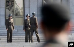 Tiga tentara Korea Utara berbindang, sementara tentara Korea Selatan (tengah) berdiri di desa perbatasan Panmunjom, Zona Demiliterisasi, Korea Selatan. (Foto: dok).