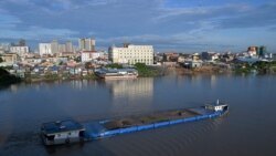 FILE - A cargo ship loaded with soil travels along the Tonle Sap river in Phnom Penh on Aug. 25, 2021.