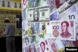 FILE - A customer is served at a counter at a foreign exchange store in Hong Kong, China, Aug. 13, 2015.