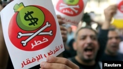 Egyptian protesters hold placards with the Arabic inscription reading ‘danger’ and shout slogans as they demonstrate against the International Monetary Fund (IMF) delegation visit, in front of the General-Prosecutor's office in Cairo, April 3, 2013.