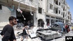 FILE - Syrians gather at a site of car bomb in the northwestern Syrian city of Idlib, Aug. 2, 2018. 