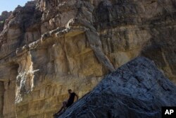 A man descends a rock on the bank of the Rio Grande, just a few feet from a cliff wall that is Mexico, in Santa Elena Canyon, at Big Bend National Park in Texas, March 27, 2017.
