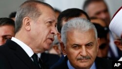 Turkey's President Recep Tayyip Erdogan (L) talks to Turkey's Prime Minister Binali Yildirim (R) as they attend the inauguration ceremony of the Melike Hatun mosque in Ankara, Turkey, Oct. 27, 2017. 