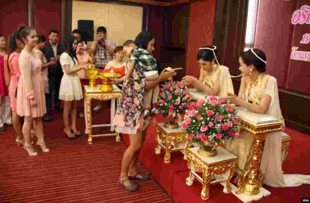 Keluarga dan tamu mengantre untuk membasuh tangan pasangan pengantin dalam upacara pernikahan di Bangkok. (VOA/Daniel Schearf)