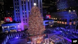 Dignitaries on stage push a button igniting the 50,000 multicolored LED lights during the 87th annual Rockefeller Center Christmas Tree lighting ceremony, Dec. 4, 2019, in New York.