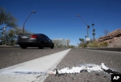 FILE - A vehicle goes by the scene of Sunday's fatality where a pedestrian was struck by an Uber vehicle in autonomous mode, in Tempe, Ariz., March 19, 2018.