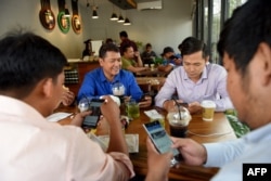 រូបឯកសារ៖ បុរសមួយក្រុមកំពុងប្រើប្រព័ន្ធអ៊ីនធឺណិតតាមទូរស័ព្ទទំនើបរបស់ពួកគេ នៅក្នុងហាងកាហ្វេមួយ នៅរាជធានីភ្នំពេញ កាលពីថ្ងៃទី១៧ ខែតុលា ឆ្នាំ២០១៨។