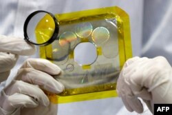 FILE - A time capsule including drawings by Israeli children, pictures of Israeli symbols and other items, which will be placed in a spacecraft to be sent to the moon, is displayed by a scientist in Yehud, east of Tel Aviv, Dec. 17, 2018.