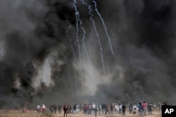 Palestinian protesters gather in front of burned tires while Israeli soldiers fire tear gas during clashes with Israeli troops along Gaza's border with Israel, east of Khan Younis, Gaza Strip, April 6, 2018.