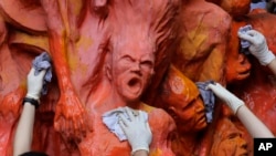 FILE - University students clean the "Pillar of Shame" statue, a memorial for those killed in the 1989 Tiananmen crackdown, at the University of Hong Kong, June 4, 2019.