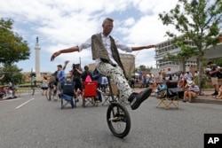 A man rides a unicycle in the street as workers prepare to take down the statue of former Confederate general Robert E. Lee while a crowd watches and cheers, in New Orleans, May 19, 2017.