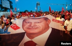FILE - Pro-government demonstrators hold a giant Turkish national flag during a march towards the Asian side of the Bosphorus Bridge in Istanbul, Turkey, July 21, 2016.