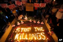 FILE - Human rights activists light candles for the victims of extrajudicial killings around the country in the wake of "War on Drugs" campaign by Philippine President Rodrigo Duterte in suburban Quezon city northeast of Manila, Philippines.