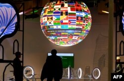 Visitors walk past a sphere featuring flags of countries of the world displayed at the pavillion of India on Nov. 8, 2017, during the COP23 U.N. Climate Change Conference in Bonn, Germany.