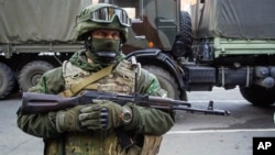 FILE - A Russia-backed rebel stands guard during preparations for a prisoner exchange in Donetsk, eastern Ukraine, Oct. 29, 2015.