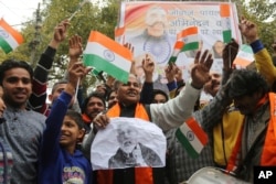 FILE - Indians wave national flags as they wait for the release of an Indian air force pilot by Pakistani authorities, in Jammu, India, March 1, 2019.
