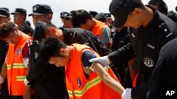 Chinese, in an orange vest, arrested over an alleged internet scam, are escorted by Chinese police officers before boarding at Phnom Penh International Airport, in Phnom Penh, Cambodia, Thursday, Oct. 12, 2017.