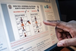 A staff member gestures towards a screen displaying how a ballot paper should be marked during the upcoming elections at the electoral commission headquarters in Kampala, Uganda, Jan. 2, 2021.
