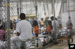 FILE - In this June 17, 2018 file photo provided by U.S. Customs and Border Protection, people who've been taken into custody related to cases of illegal entry into the United States sit in one of the cages at a facility in McAllen, Texas.